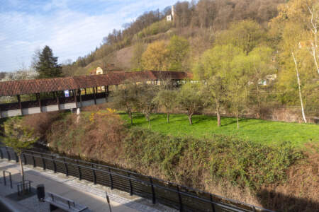 Ausblick vom Hotel Alter Packhof auf den Uferweg, eine überdachte Brücke und die grüne Umgebung