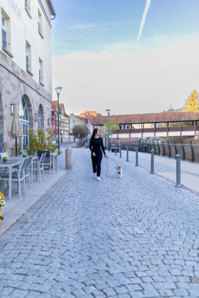 Frau mit Hund auf dem Uferweg vor dem Hotel Alter Packhof