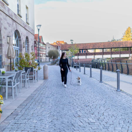 Frau mit Hund auf dem Uferweg vor dem Hotel Alter Packhof