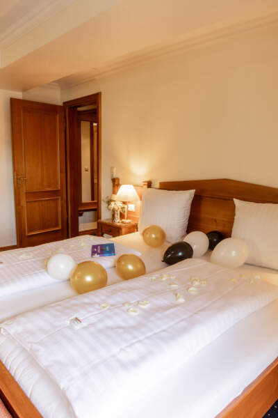 Doppelzimmer im Hotel Alter Packhof mit dekorierten Betten, Rosenblättern und Luftballons
