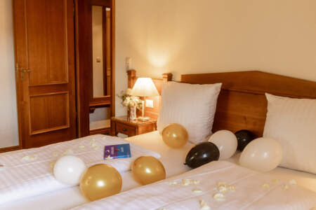 Doppelzimmer im Hotel Alter Packhof mit dekorierten Betten, Rosenblättern und Luftballons