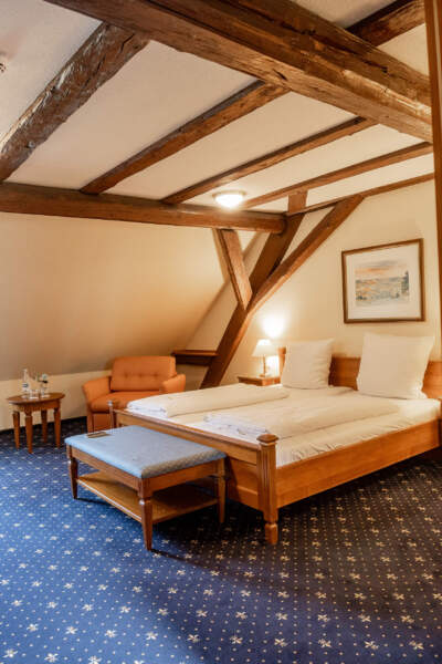 Geräumiges Doppelzimmer im Hotel Alter Packhof mit sichtbaren Holzbalken und Sitzecke