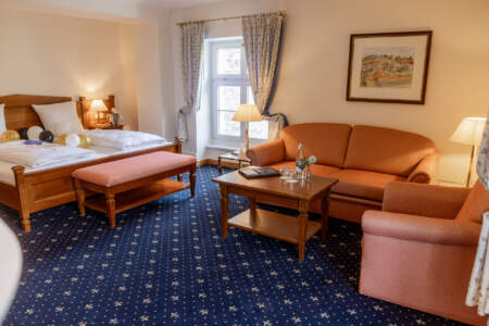 Geräumiges Doppelzimmer im Hotel Alter Packhof mit Sitzecke und dekoriertem Bett