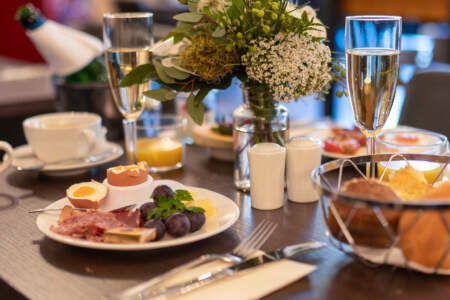 Gedeckter Frühstückstisch im Hotel Alter Packhof mit Brötchen, Ei, Obst und Blumen