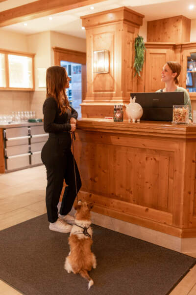 Gast mit Hund an der Rezeption des Hotel Alter Packhof im Gespräch mit einer Mitarbeiterin