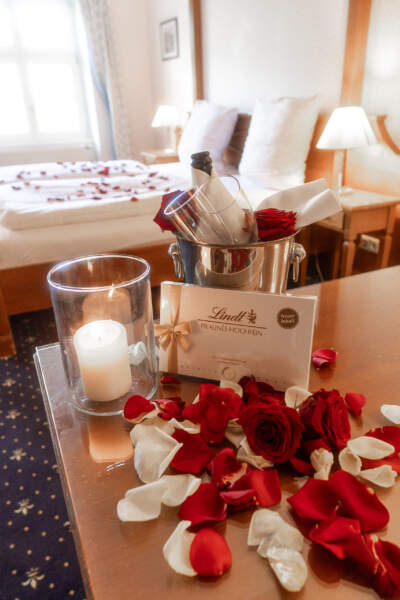 Romantisches Arrangement im Hotel Alter Packhof mit Rosen, Kerze, Pralinen und gekühltem Getränk