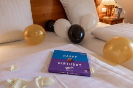 Dekoriertes Bett im Hotel Alter Packhof mit Luftballons, Rosenblättern und Pralinen