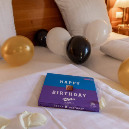 Dekoriertes Bett im Hotel Alter Packhof mit Luftballons, Rosenblättern und Pralinen