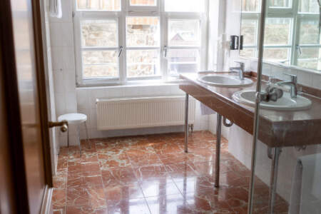 Helles, geräumiges Hotelbadezimmer mit Dusche, Waschbecken, großem Spiegel und Marmorboden.