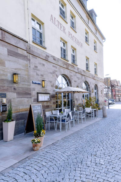 Außenansicht des Hotels Alter Packhof mit historischer Fassade, Außenterrasse und Sitzplätzen vor dem Eingang.