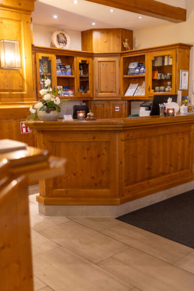 Gemütliche Hotelrezeption aus Holz mit Empfangstresen, Informationsmaterial und Blumen im Hotel Alter Packhof.