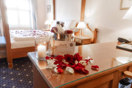Romantisches Zimmerarrangement im Hotel Alter Packhof mit Rosen, Kerze, Pralinen und gekühltem Getränk
