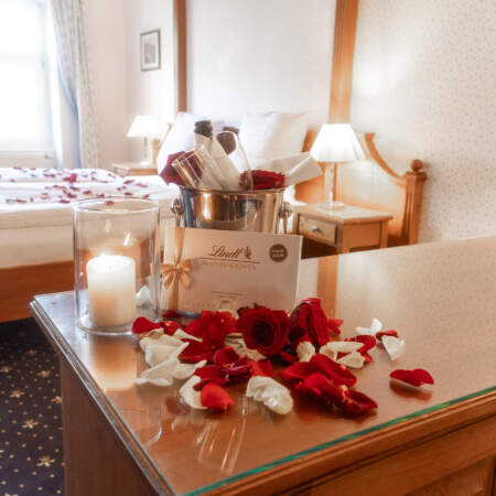 Romantisches Zimmerarrangement im Hotel Alter Packhof mit Rosen, Kerze, Pralinen und gekühltem Getränk
