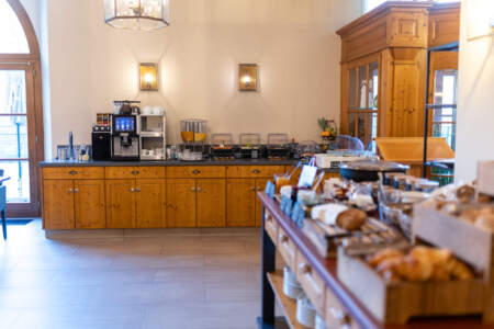 Helles Frühstücksbuffet im Hotel mit Backwaren, Getränken, Kaffeeautomat und verschiedenen Speisen.